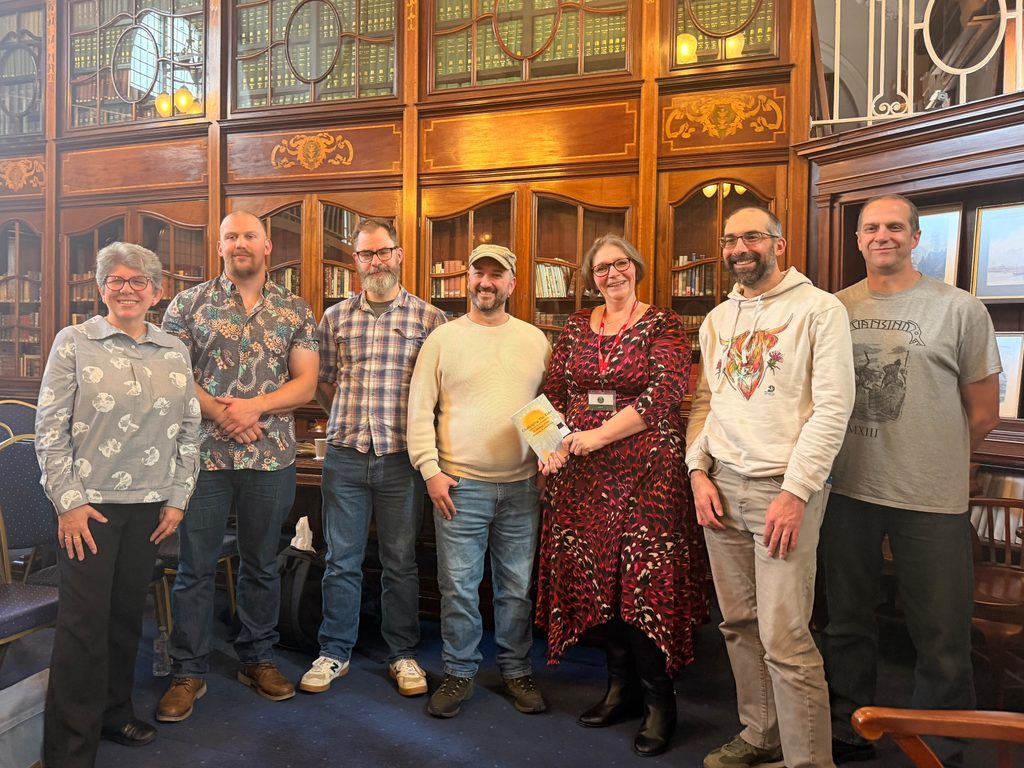 Seven authors with stories in the Challenging the Tides anthology stand in the James Reckitt Reading Room in Hull Central Library